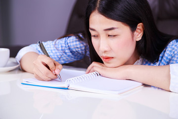 stressed business woman sitting at her desk and writes a note on the notebook