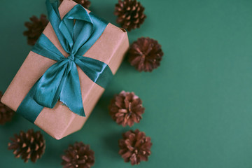 Obraz na płótnie Canvas Christmas gift box with pine cones on green background