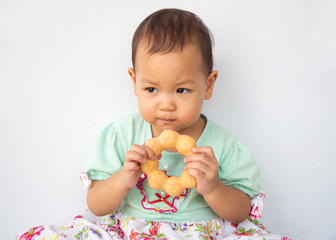 Little girl used two hands holding donut and eat. Sweet dessert. Portrait on white background. Asian children.