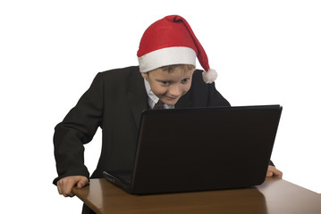 Boy in a Santa Claus hat at the computer.