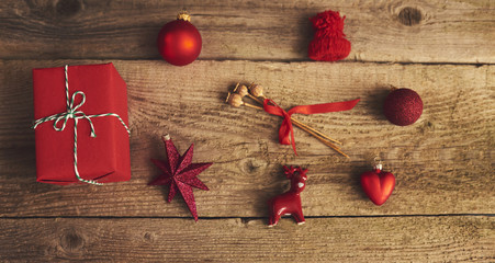 Christmas gift box and red decoration over wood background