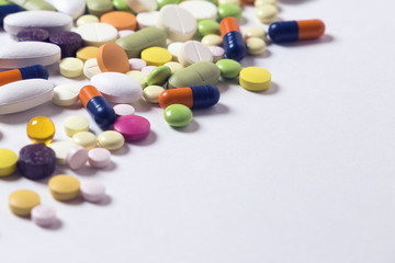 a lot of multicolored pills and capsules on the white background with copy space