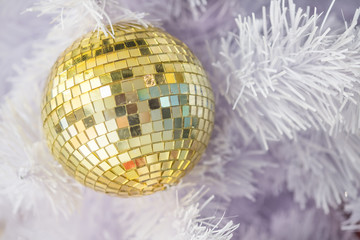 Close up of golden x'mas ball ornaments on white christmas tree.