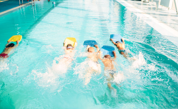 Boys swimming with plank in a pool race
