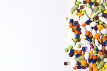 a lot of multicolored pills and capsules on the white background with copy space