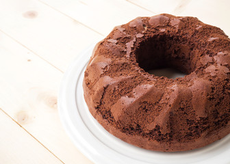 Chocolate cake on white plate. Over wooden table.