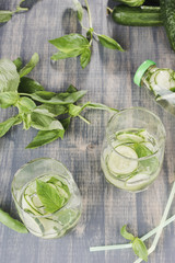 Glasses of cucumber detox water. Homemade cold gin tonic with basil on wooden table