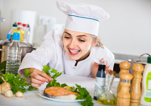 young cook with prepared salmon in professional kitchen