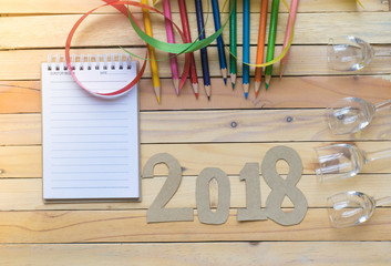 notepad with number paper 2018 and ribbon on wood backgorund for happy new year image. And welcome new year photo.