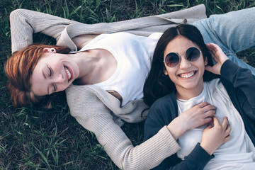 Two best friends lying on the grass and smiling