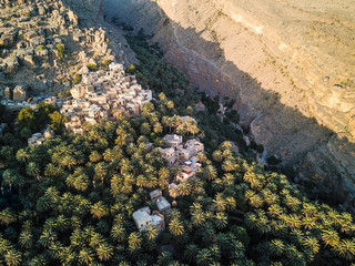 Aerial drone view of an old traditional Omani mud village in the mountains among date palm trees. Misfat Al Aberyeen, Oman.