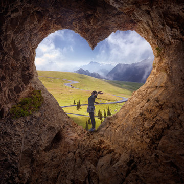 Lone woman in heart shape cave towards the idyllic scenery