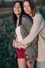 Two girls hugging with eyes closed standing outdoors