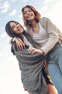 Two cute girls hugging under sky. Best friends
