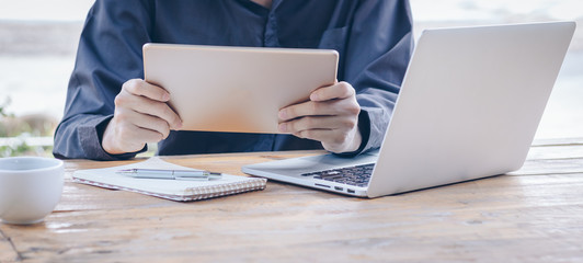Businessman using tablet working with laptop and coffee.