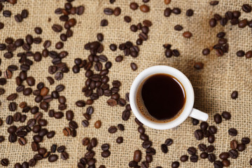 Cup of coffee on sackcloth with coffee beans