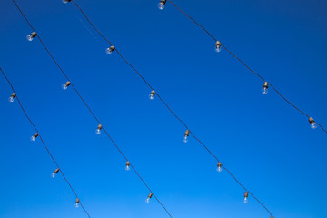 Vintage antique hanging light bulbs at the blue sky. Holidays and business good idea concept.