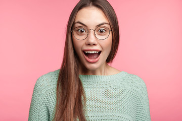 Excited amazed young woman looks at fashionable clothes in shopping mall, doesn`t know what to buy, amazed with high discounts, wants to renew wardrobe. People, unexpectedness, excitement concept