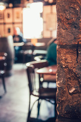 Abstract defocused shot of some chairs and people in a pub with bright light streaming through a window at the far end