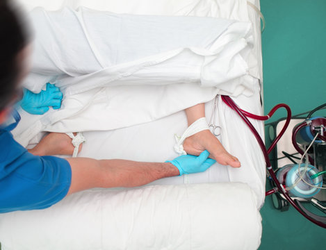 Male doctor touches the patient's feet to assess the blood motion in the limbs