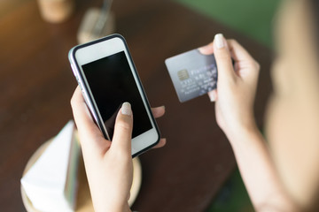 Girl using cell phone for online shopping by credit card at coffee shop