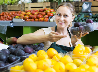 Portrait of smiling woman selling ripe fresh plums