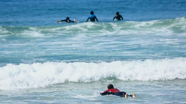 Guy swimming on surfing board in ocean diving into wave, beginner learning surf