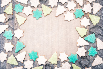 Christmas gingerbread cookies on a baking paper. Cookies covered with multi colored icing in pale pastel colors shaped as fir-tree and star