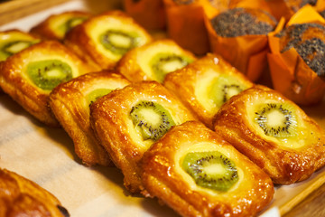 Muffin cup cake and puff pastry cake with kiwi on wooden board