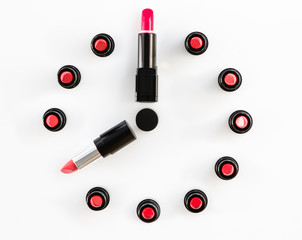 clock face and arrows on white background made from lipsticks