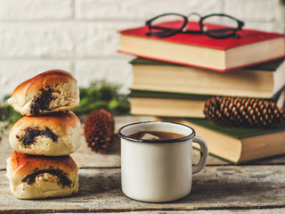 a mug of hot and fragrant tea with buns filled with poppy seeds and also reading books
