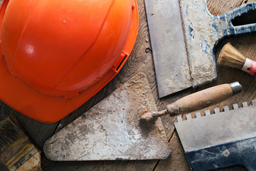 A helmet, a trowel, brushes and spatulas on a wooden table