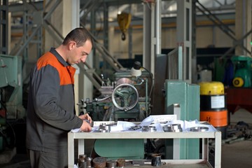 Fototapeta na wymiar metalworking industry: factory man worker in uniform working on lathe machine in workshop