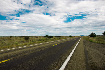 Straight wet road leading throught Arizonas beautiful prairie