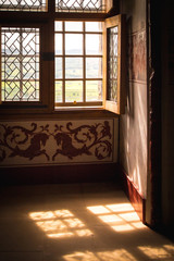 Sunlight streams through an old wooden window in an old english house with ornate decor