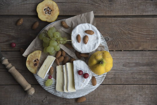 camembert cheese, fruits and nuts on the wooden table 