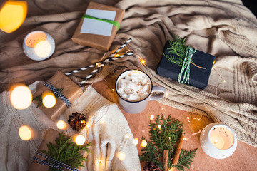 Cup with marshmallow and Christmas lights, candles, gift boxes