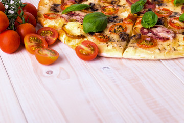 Pizza with Salami Vegetables and Spices on a white wooden background with copy space.
