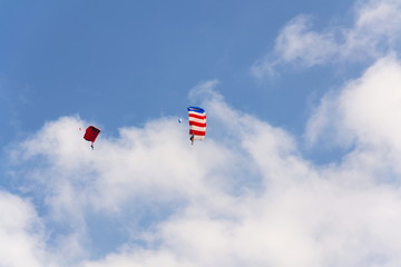 Two parachutists skydiving with colorful parachute clouds blue sky background