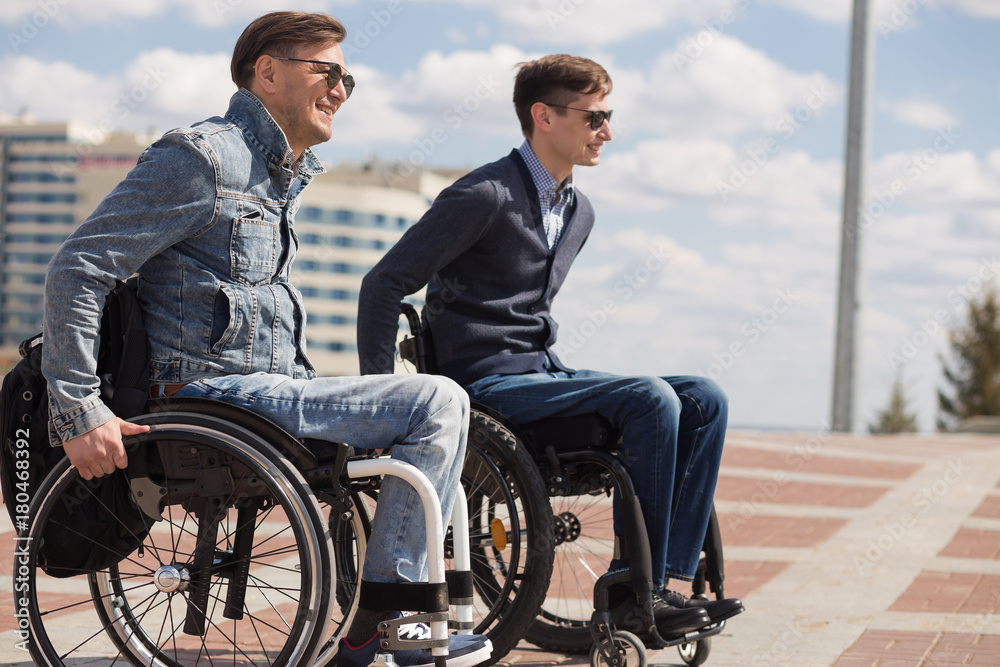 Wall mural young man sitting on a wheelchair with his friend