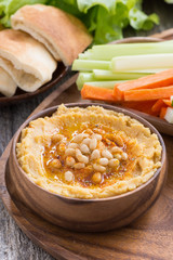 Traditional hummus in bowl with pita bread and vegetables, vertical