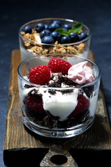 various desserts with fresh berries and cream on dark background, vertical