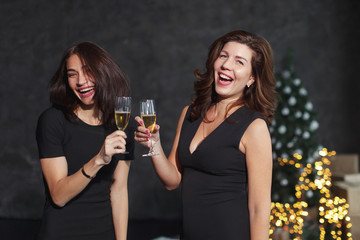Beautiful girls in evening dresses with glasses of champagne to celebrate the New year