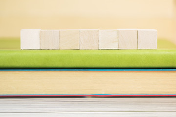 Plain wooden cube on book.  selective focus on wooden cube block on green notebook 