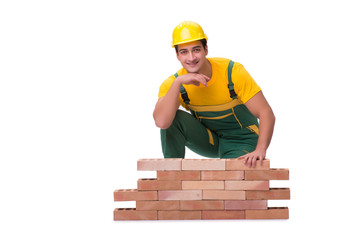 The handsome construction worker building brick wall