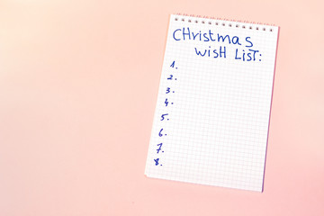 christmas wish list notebook on pink background