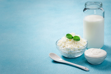 Fresh milk sour cream yogurt cottage cheese in glass bowls on blue background. Selective focus, copy space. 