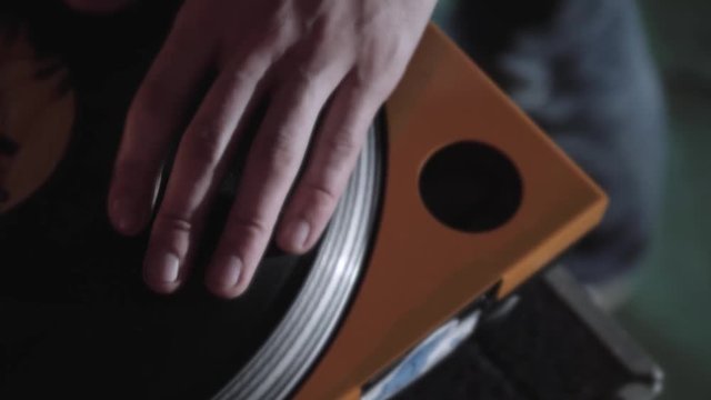 Disc jockey scratch vinyl record with music on turntable records player. Turntables vinyl disc in focus. Play music on dj audio equipment in night club. Close up,focus on djs hand on disc. Turntables