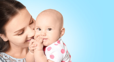Portrait of happy young woman with cute baby on color background