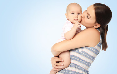 Portrait of happy young woman with cute baby on color background